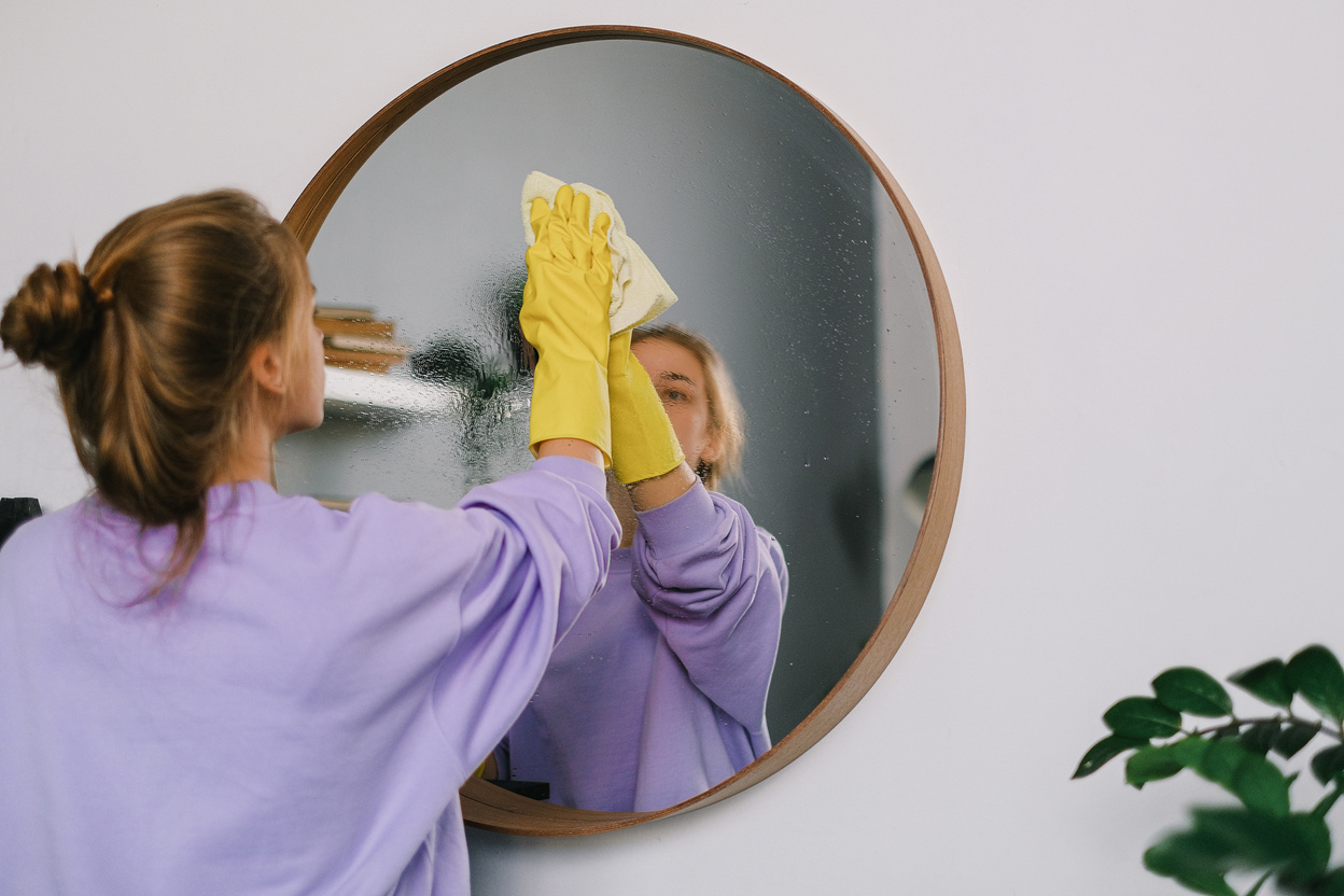 Woman Wearing Glove Cleaning a Mirror